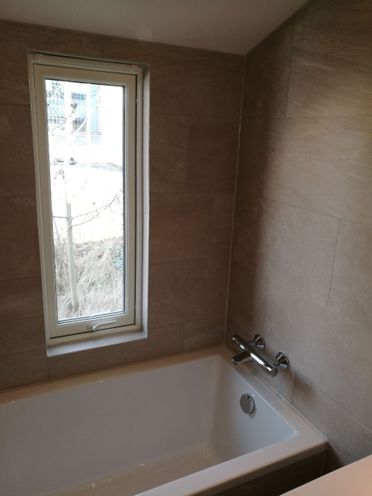 Renovert bad med badekar og matte store fliser på vegg